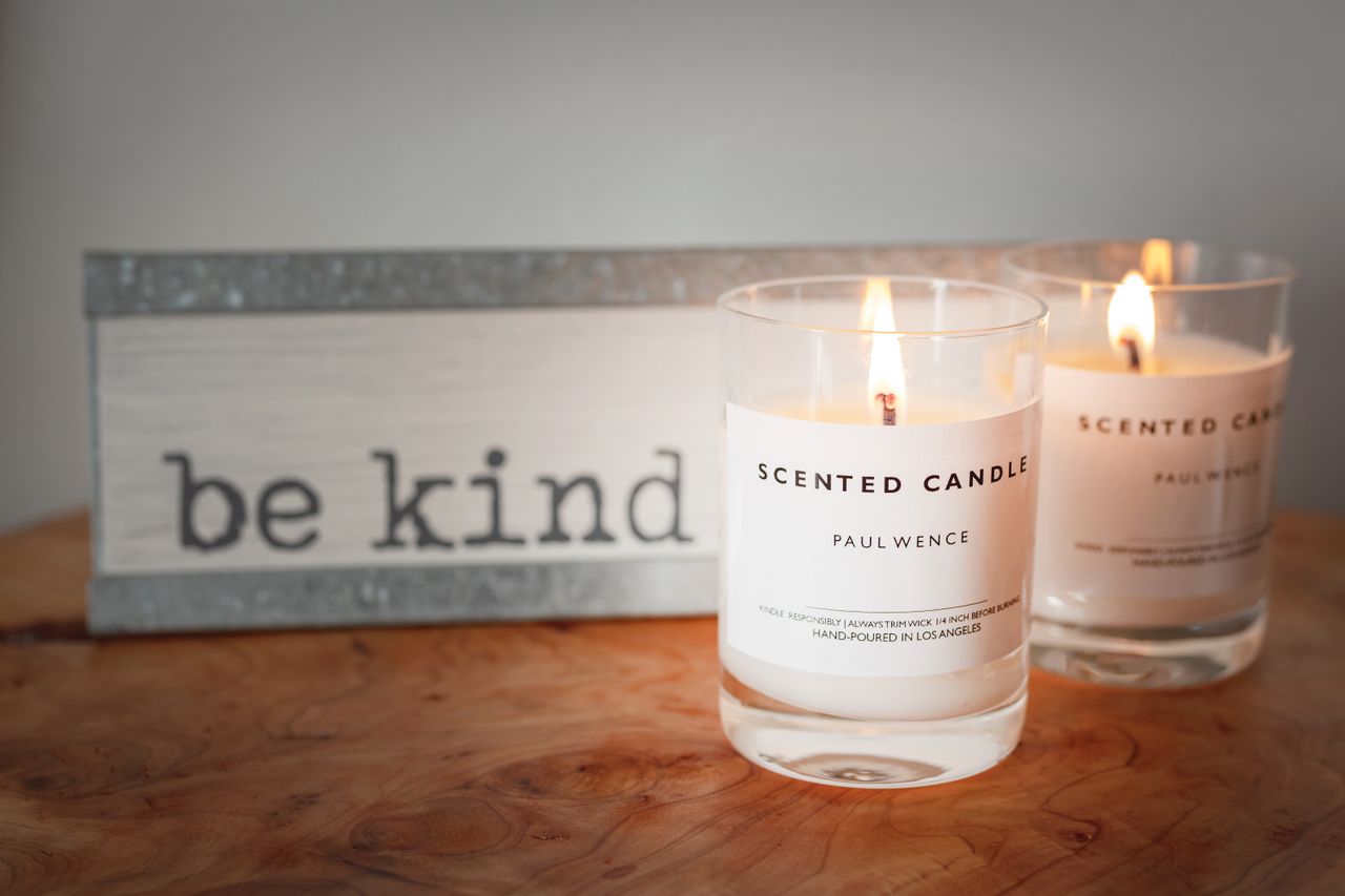 our-journey-02 A warm setting with lit scented candles and a motivational 'be kind' sign for a cozy ambiance.