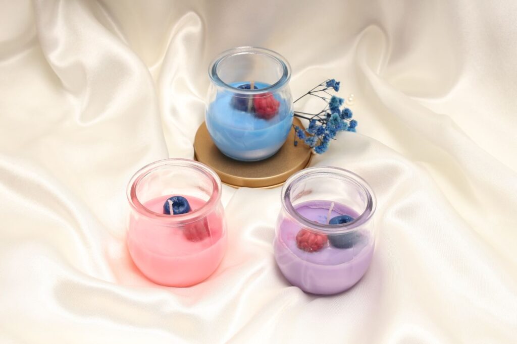 Three colorful scented candles on a luxurious satin fabric, creating a serene atmosphere.
