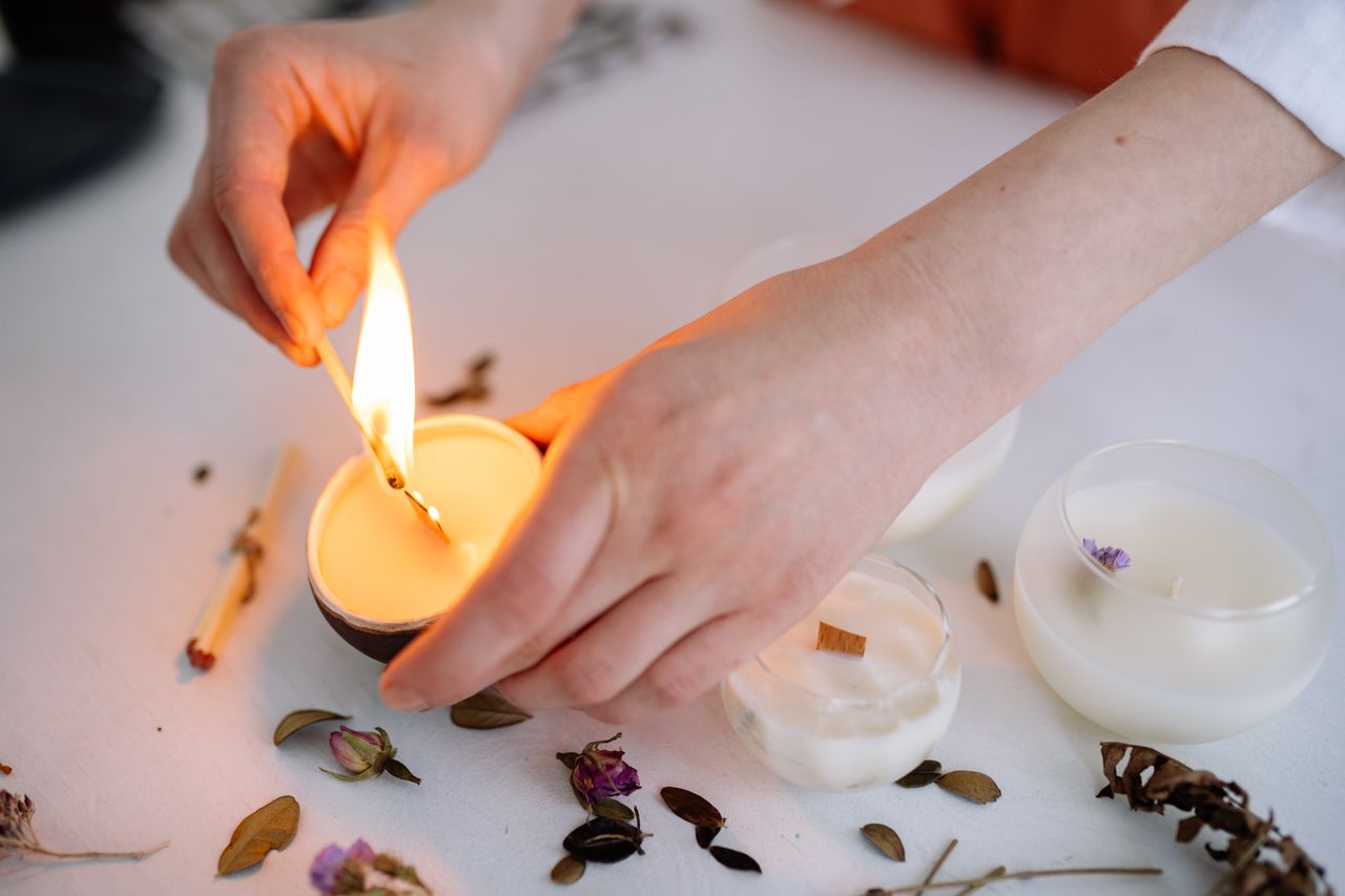 services-01 A serene moment captured as hands light a scented candle on a white table.